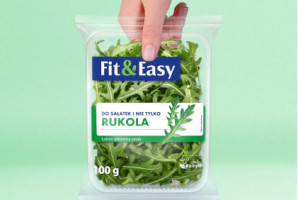 Opakowanie rukoli Fit&Easy trzymane przez rękę na jasnozielonym tle, z napisem 'Do sałatek i nie tylko - rukola, lekko pikantny smakk