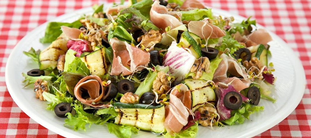 Salad with prosciutto, melon sprouts, grilled zucchini and walnuts