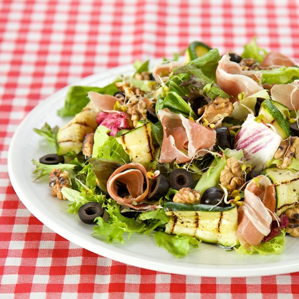 Salad with prosciutto, melon sprouts, grilled zucchini and walnuts